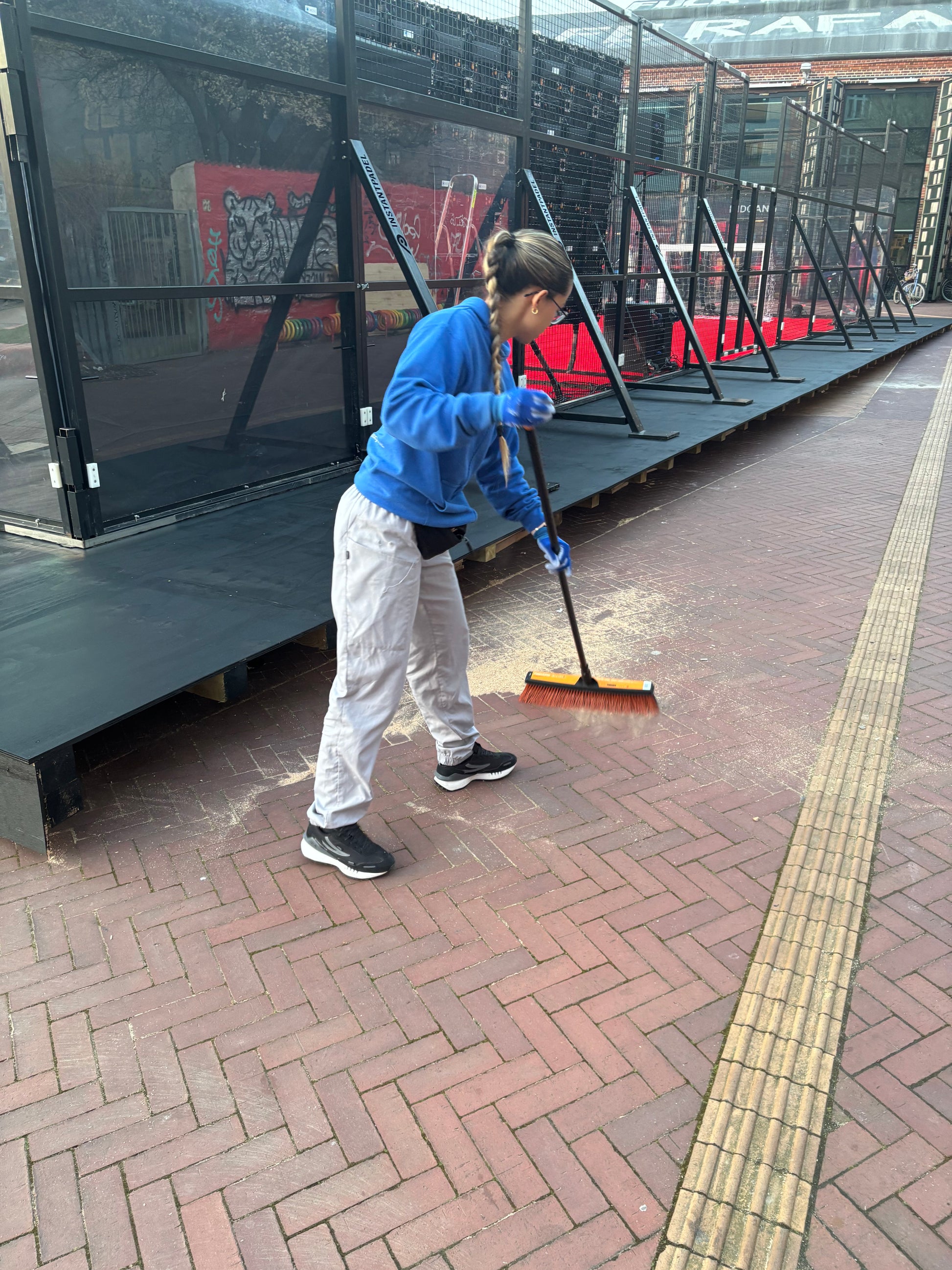 Worker sweeping the pavement as part of party and event cleaning service in Copenhagen.