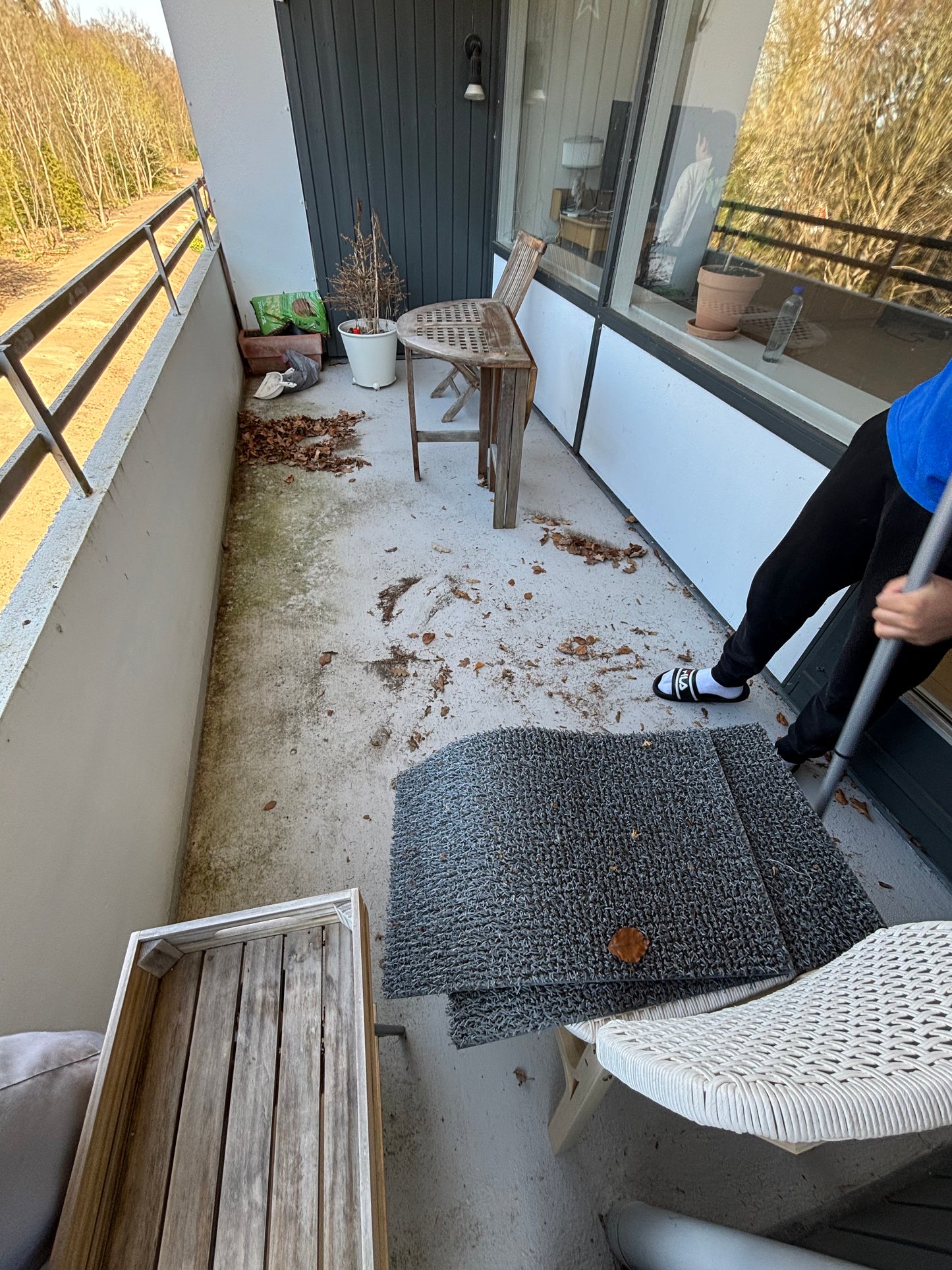 A person cleaning a dirty balcony in Copenhagen, removing leaves and debris to restore its pristine appearance.