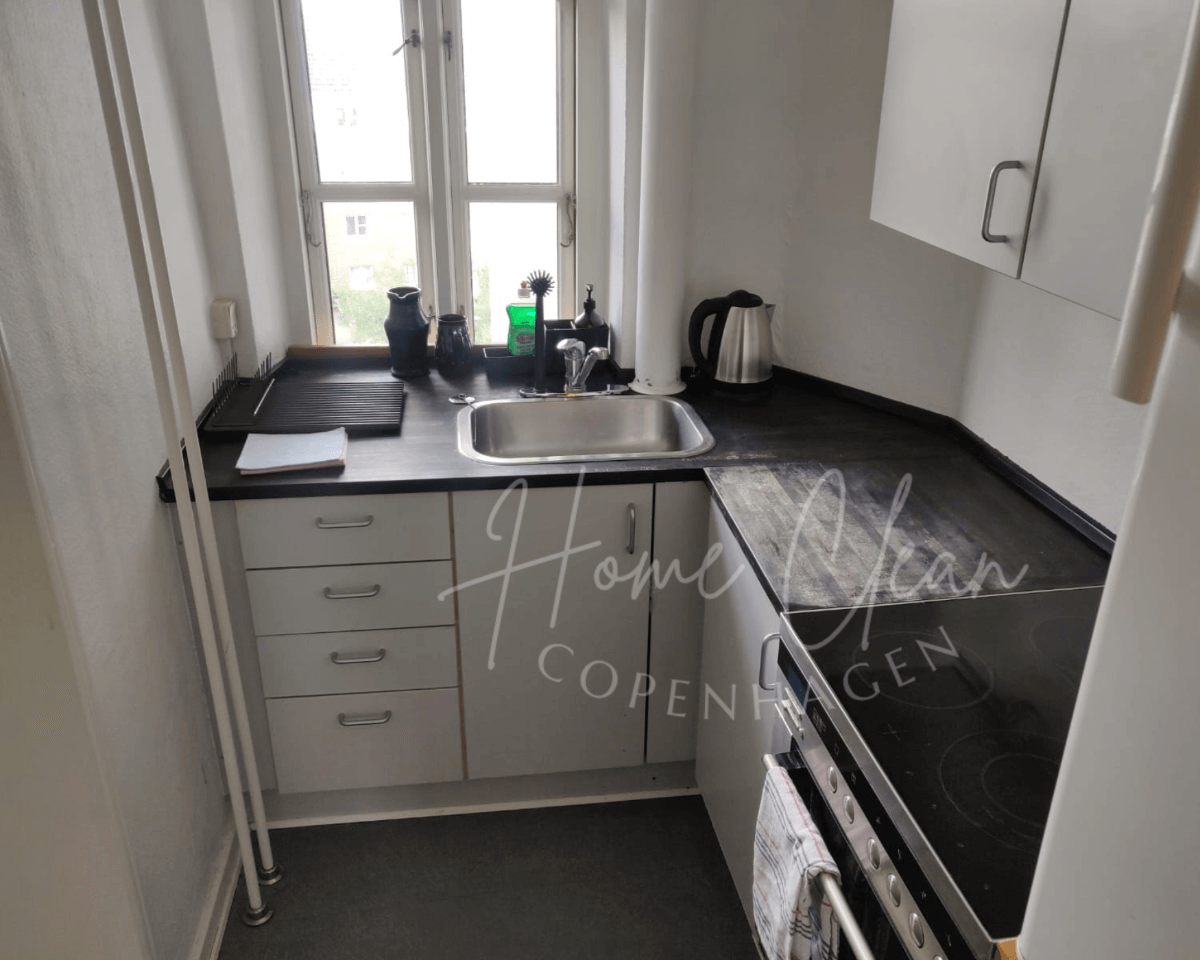 Modern kitchen in Copenhagen with clean countertops and a stainless steel sink, showcasing deep cleaning services.
