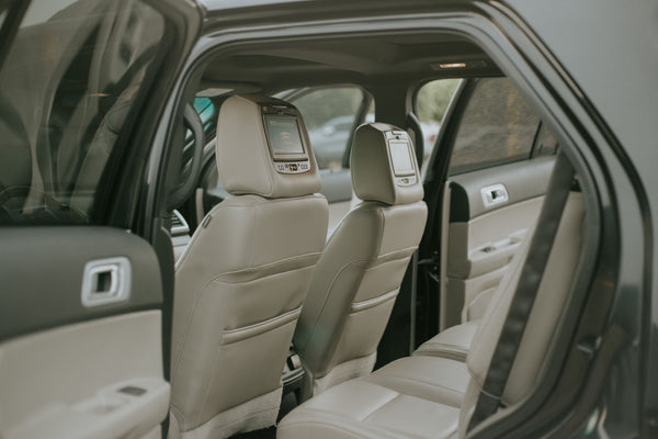 Beige leather seats inside a car, seen through an open rear door