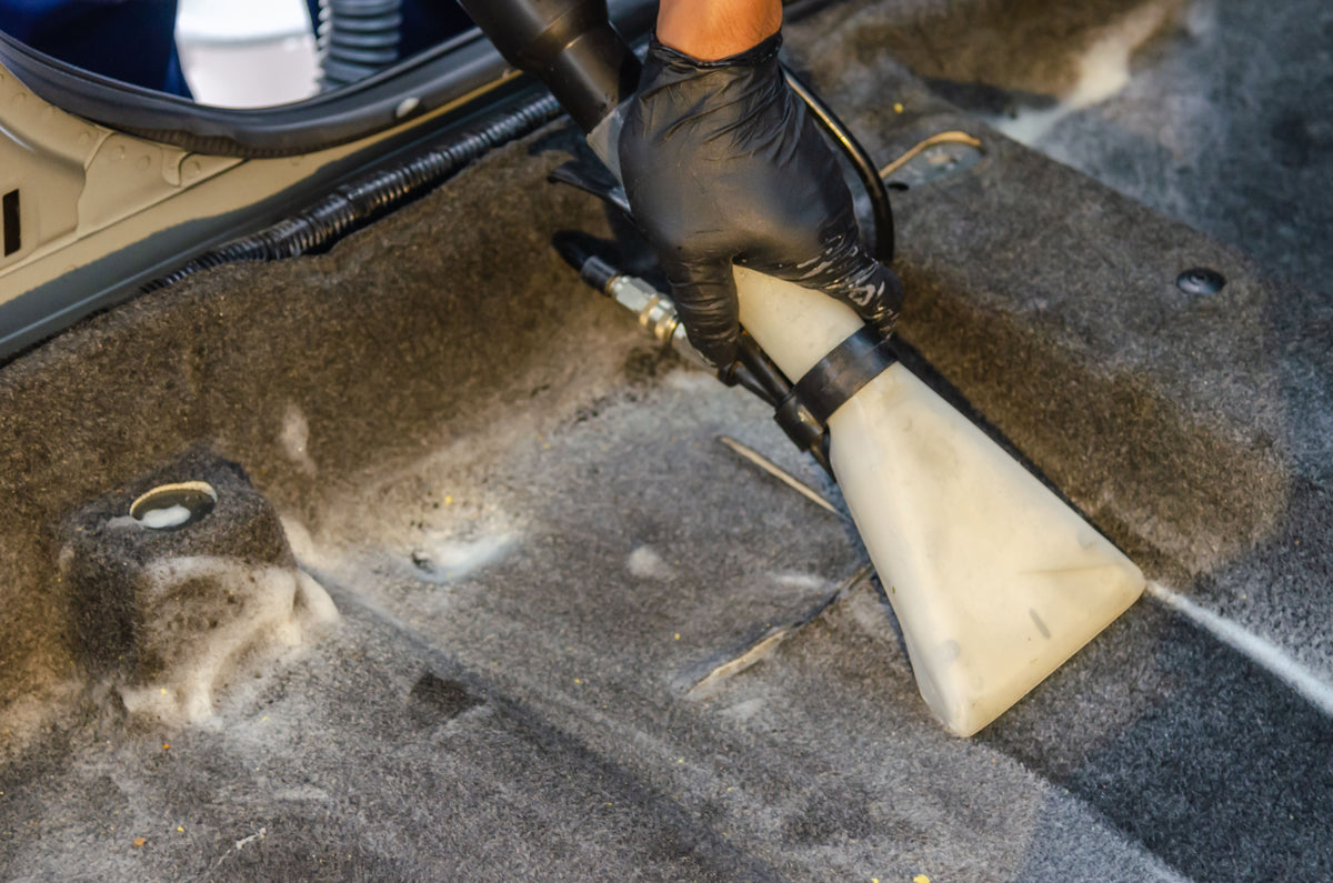 Deep cleaning the car carpet with an extraction machine